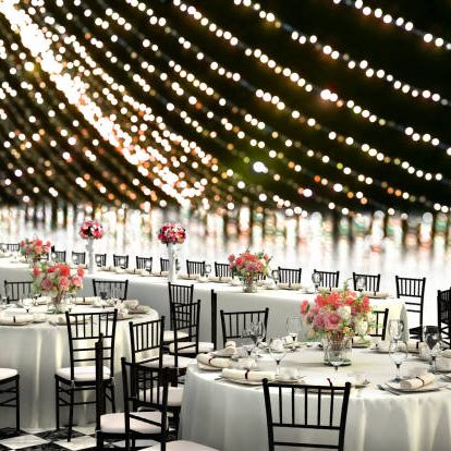 3D Illustration of a wedding reception venue decorated in white with ten seat round tables and a head table on a bokeh background